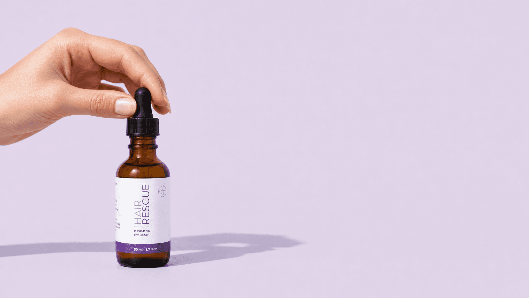 A hand holding the dropper above a Hair Rescue serum bottle